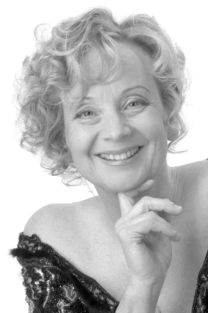 Schwarz-Weiß-Porträt von Barbara Baier mit lockigem Haar, lächelnd, das Kinn auf die Hand gestützt